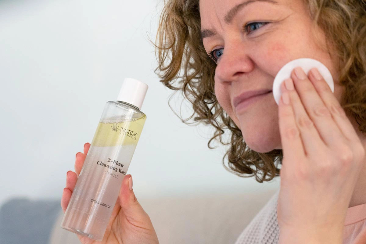 Die Frau benutzt 2-Phase Cleansing Wasser mit CBD von Nordic Cosmetics. Sie tupft das Produkt mit einem Wattepad über ihr Gesicht.