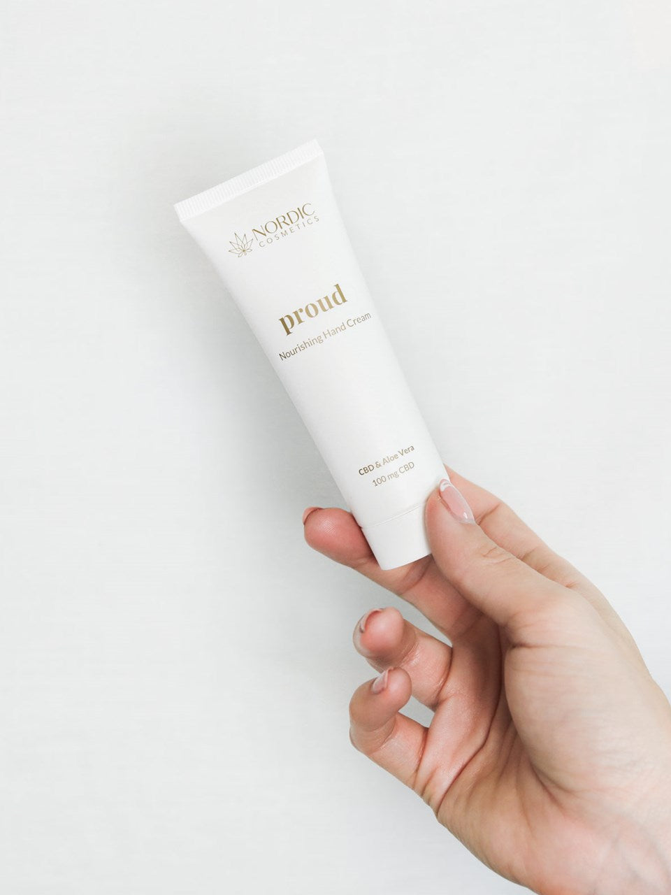 Eine Frauenhand hält eine Tube des Pflegende Handcreme.