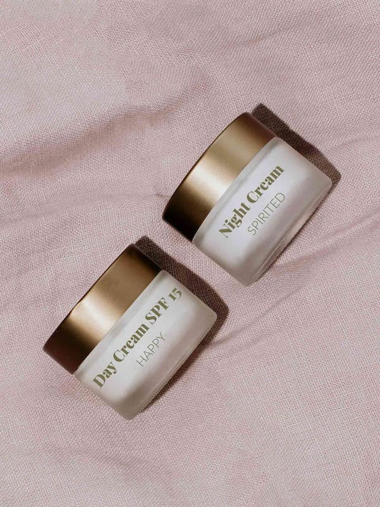 Die Container von Feuchtigkeitsspendende Tagescreme und Regenerierende Nachtcreme liegen auf einer pinken Decke