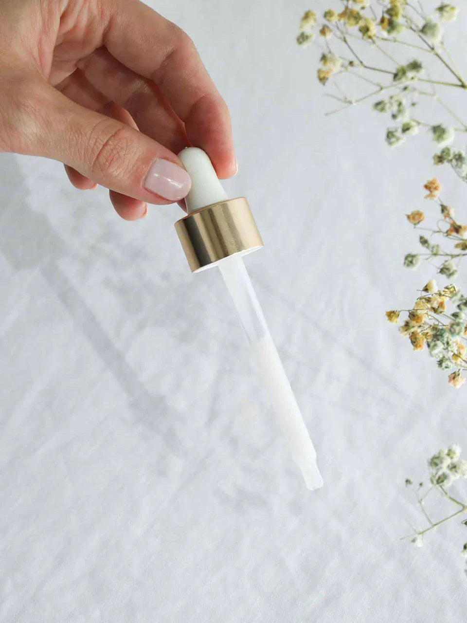Die Pipette des Produktes Feuchtigkeitsspendendes Gesichtsserum wird von einer Hand festgehalten