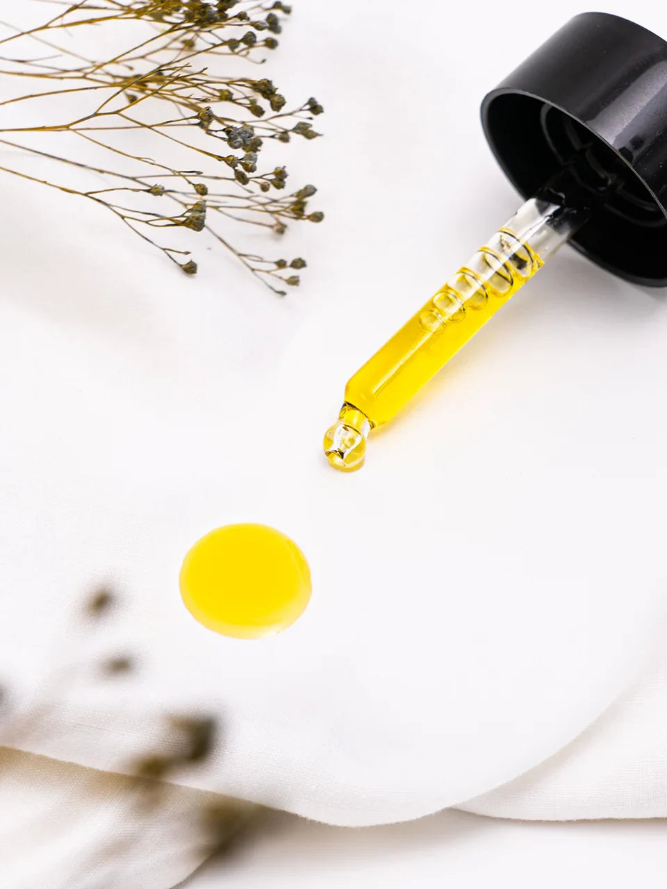 Eine Pipette liegt auf einem weißen Untergrund. Sie tropft auf ein weißes Tuch.