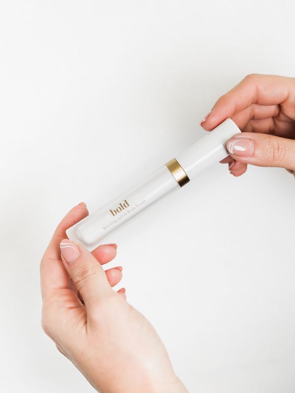 Zwei Hände die Stärkendes Wimpernserum halten