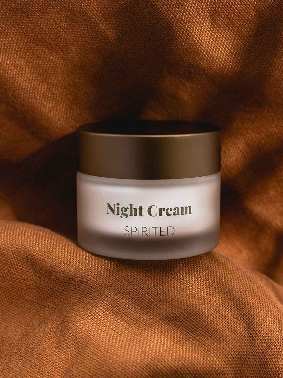 Eine Dose des Regenerierende Nachtcreme liegt auf einem orangenen Tuch.