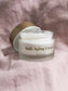 Eine offene Dose des Revitalisierende Anti-Aging Creme mit CBD liegt auf einem pinken Tuch.