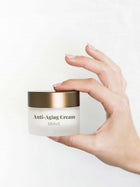 Frauenhände halten eine Dose des Revitalisierende Anti-Aging Creme mit CBD.
